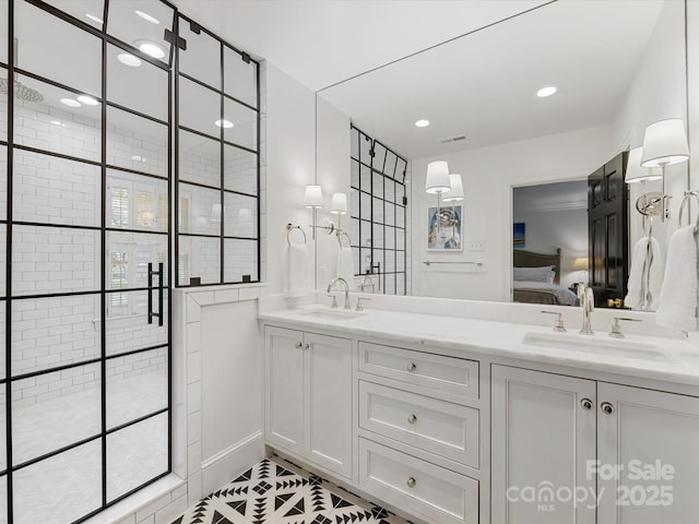 ensuite bathroom with connected bathroom, double vanity, a stall shower, and a sink