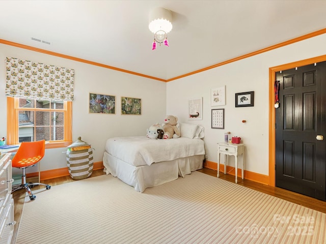 bedroom with baseboards, visible vents, wood finished floors, and ornamental molding