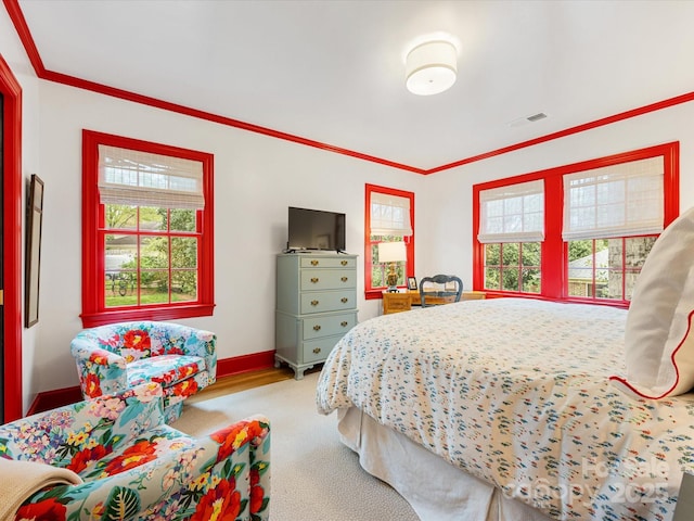 carpeted bedroom featuring ornamental molding, baseboards, multiple windows, and visible vents