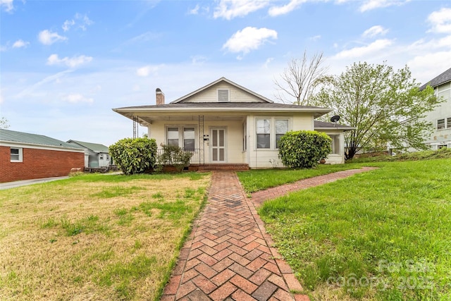 bungalow with a porch, a chimney, and a front yard