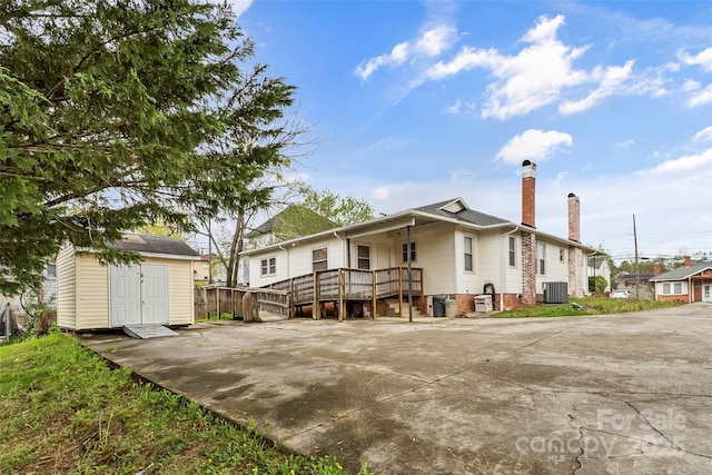 back of property with a shed, an outdoor structure, cooling unit, and a chimney