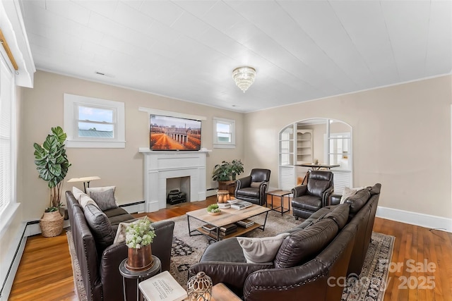 living area featuring a fireplace with flush hearth, a baseboard radiator, wood finished floors, and baseboards