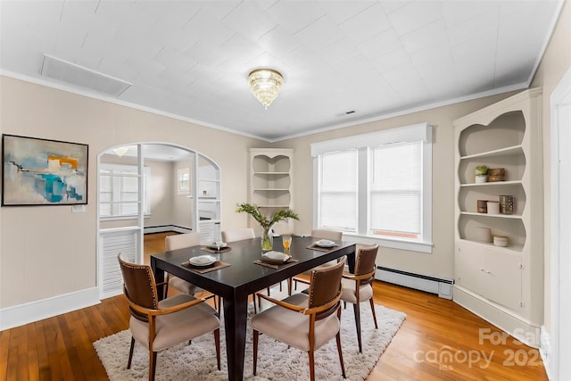 dining area with baseboards, arched walkways, ornamental molding, light wood finished floors, and a baseboard heating unit