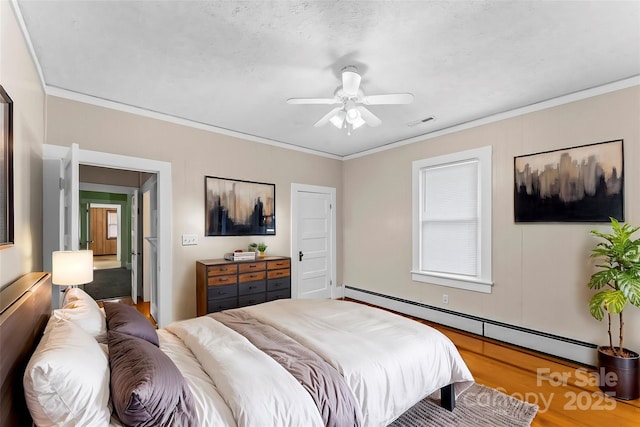 bedroom with crown molding, visible vents, ceiling fan, a baseboard radiator, and wood finished floors