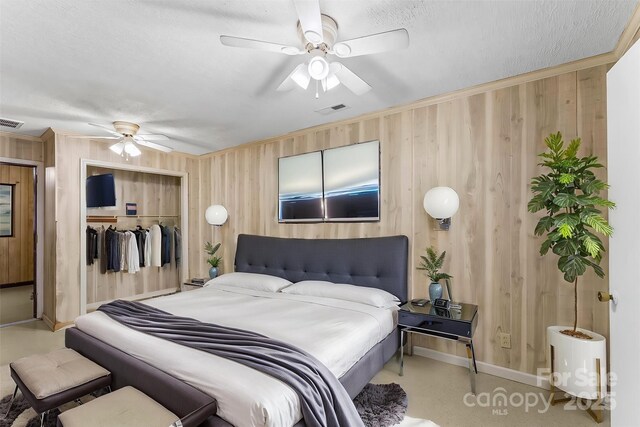 bedroom with crown molding, visible vents, a closet, and wood walls