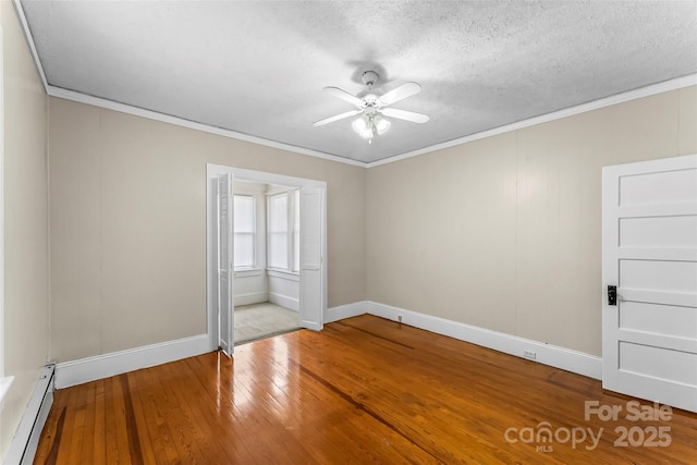 empty room featuring a baseboard heating unit, a textured ceiling, crown molding, hardwood / wood-style floors, and ceiling fan
