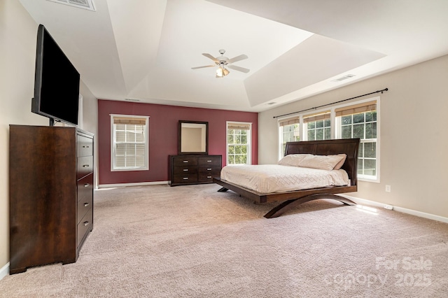 carpeted bedroom featuring a tray ceiling, baseboards, ceiling fan, and visible vents
