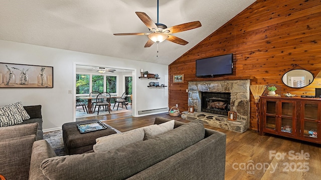 living area featuring wood walls, a baseboard radiator, ceiling fan, and wood finished floors