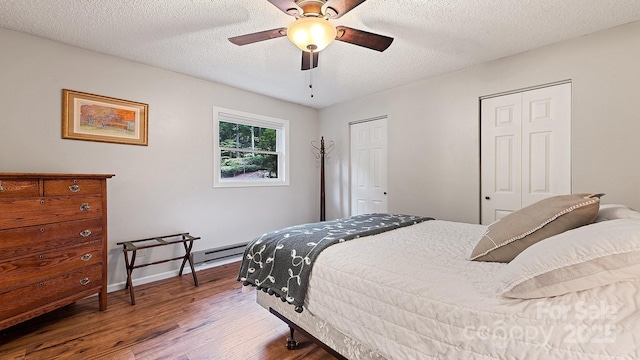 bedroom with two closets, a textured ceiling, ceiling fan, and wood finished floors