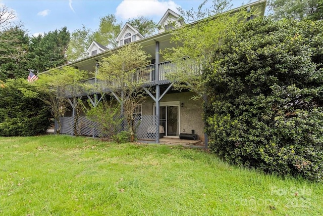 rear view of property with a lawn and stucco siding