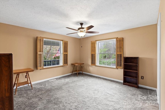 carpeted empty room with visible vents, baseboards, a ceiling fan, and a textured ceiling