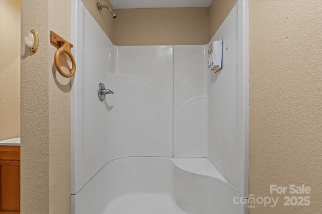 bathroom with a textured wall and walk in shower