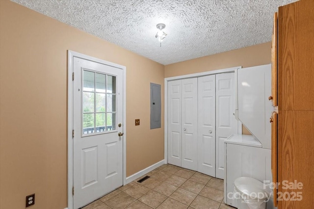 laundry room with baseboards, electric panel, light tile patterned floors, a textured ceiling, and visible vents