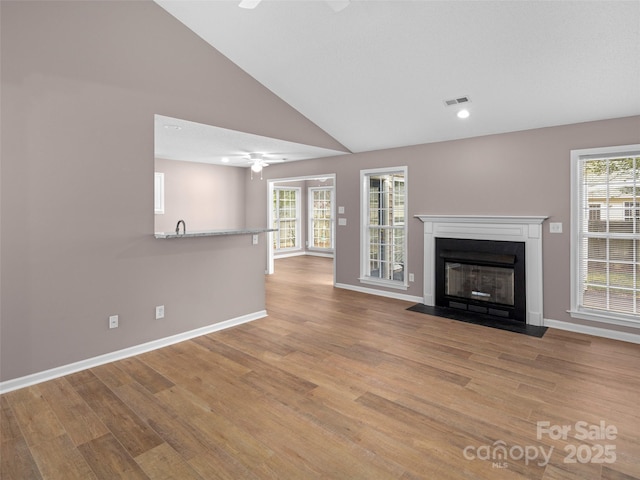 135 S Sunberry Trl, Fletcher, NC 28732 - unfurnished living room featuring a fireplace with flush hearth, light wood-style floors, a ceiling fan, and plenty of natural light