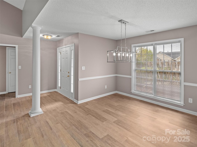 135 S Sunberry Trl, Fletcher, NC 28732 - unfurnished dining area with light wood-style flooring, decorative columns, baseboards, and a textured ceiling