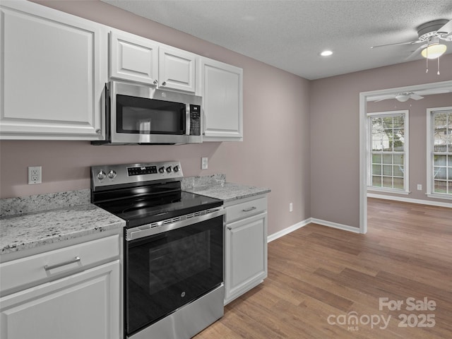 135 S Sunberry Trl, Fletcher, NC 28732 - kitchen featuring light wood-type flooring, baseboards, white cabinetry, ceiling fan, and stainless steel appliances