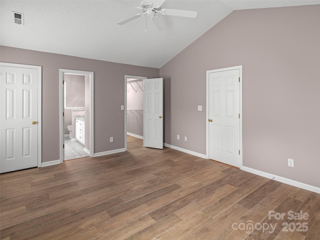 135 S Sunberry Trl, Fletcher, NC 28732 - unfurnished bedroom with connected bathroom, visible vents, wood finished floors, lofted ceiling, and baseboards