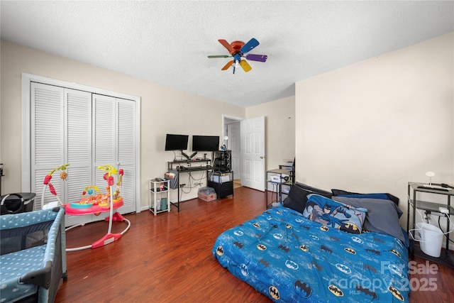 bedroom with ceiling fan, wood finished floors, a textured ceiling, and a closet