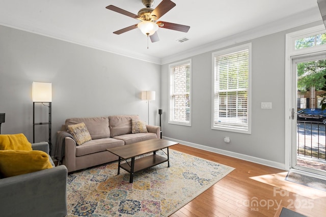 living room with baseboards, ornamental molding, a ceiling fan, visible vents, and hardwood / wood-style flooring
