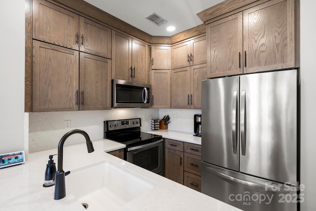 kitchen featuring recessed lighting, light countertops, visible vents, stainless steel appliances, and a sink