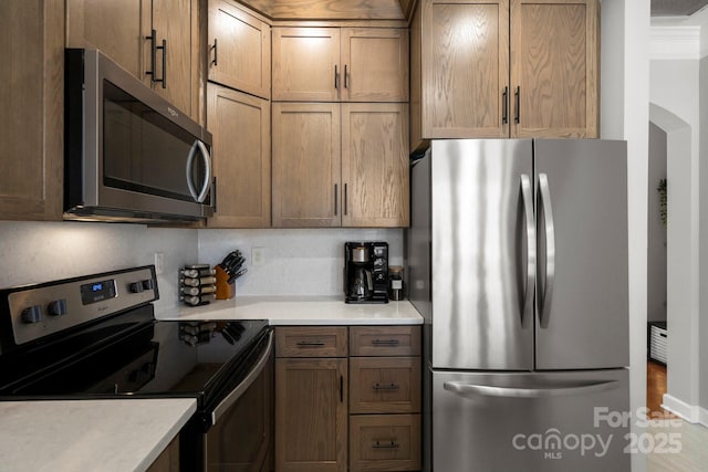 kitchen featuring stainless steel appliances, arched walkways, and light countertops
