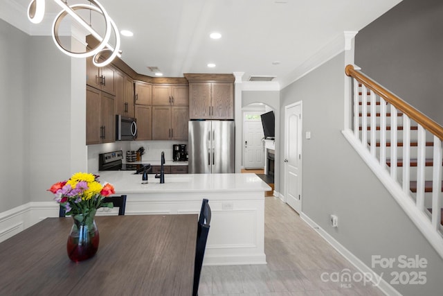 kitchen featuring arched walkways, a peninsula, light countertops, and appliances with stainless steel finishes