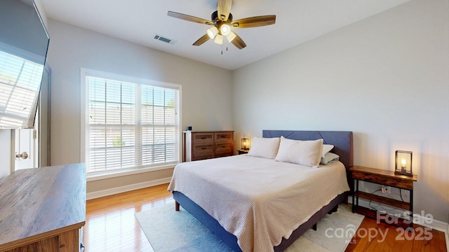bedroom featuring wood finished floors, ceiling fan, baseboards, and visible vents