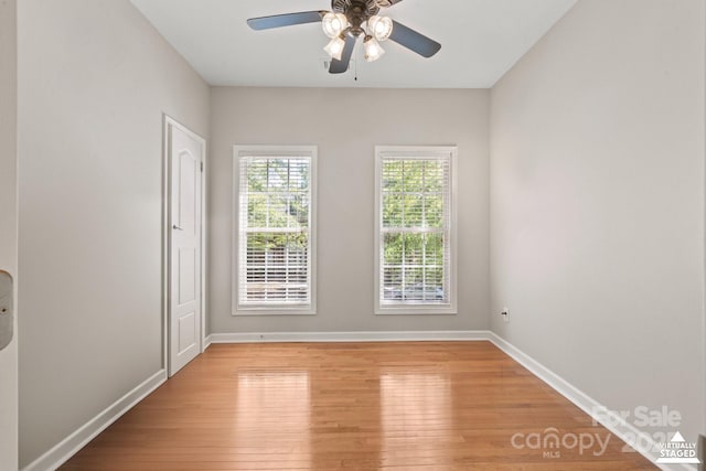spare room with light wood-type flooring, baseboards, and ceiling fan