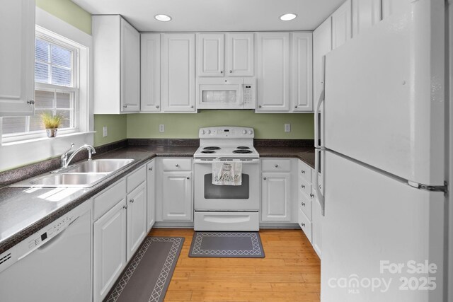 kitchen with white appliances, white cabinets, recessed lighting, and a sink