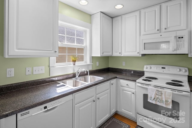 kitchen with recessed lighting, white appliances, a sink, white cabinetry, and dark countertops
