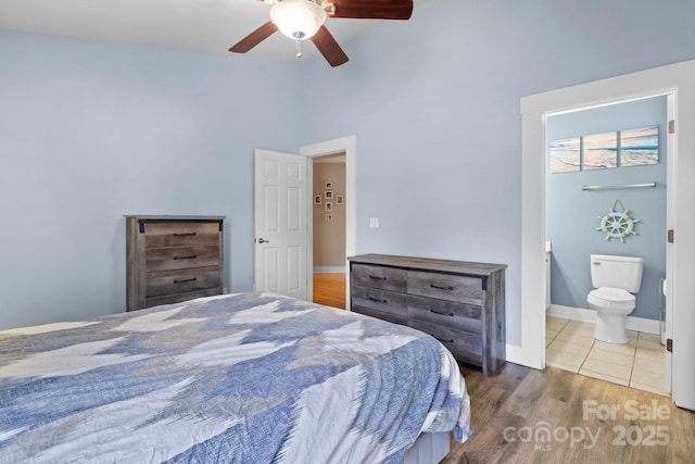 bedroom with connected bathroom, wood finished floors, a ceiling fan, high vaulted ceiling, and baseboards
