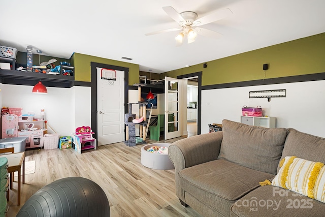 living room with a ceiling fan, visible vents, and wood finished floors