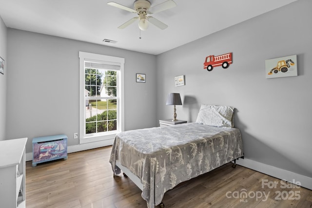 bedroom featuring baseboards, visible vents, wood finished floors, and a ceiling fan