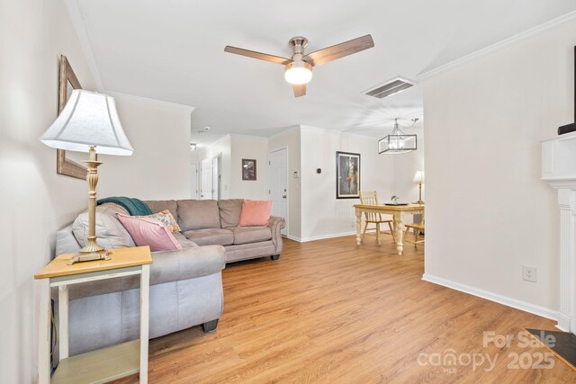 living area featuring crown molding, light wood-style floors, ceiling fan with notable chandelier, visible vents, and baseboards