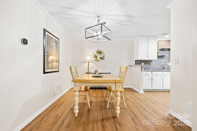 dining area featuring light wood finished floors, baseboards, and ornamental molding