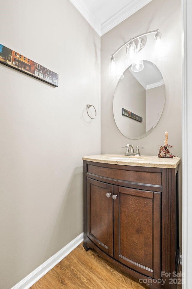 bathroom with wood finished floors, vanity, baseboards, and ornamental molding