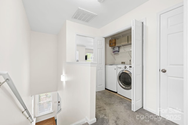 clothes washing area with visible vents, baseboards, laundry area, washing machine and dryer, and light colored carpet