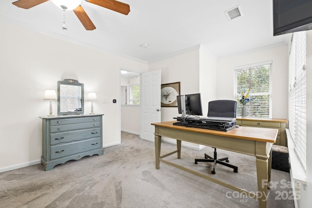 home office with baseboards, light carpet, crown molding, a ceiling fan, and visible vents
