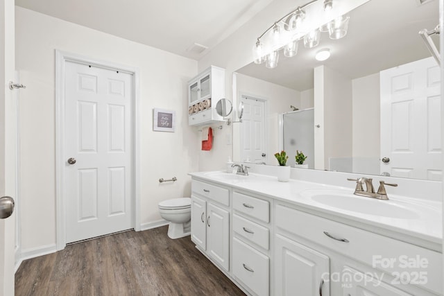 bathroom featuring a sink, double vanity, a stall shower, and wood finished floors