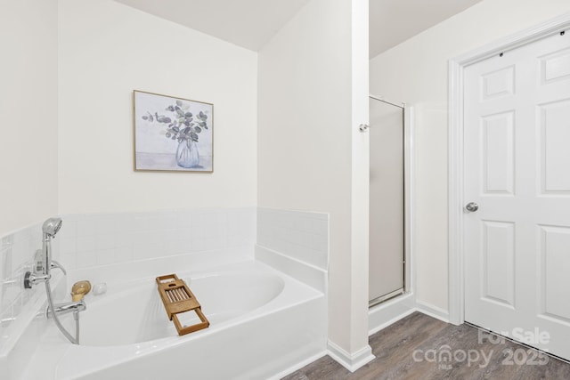 full bathroom with a bath, wood finished floors, baseboards, and a stall shower