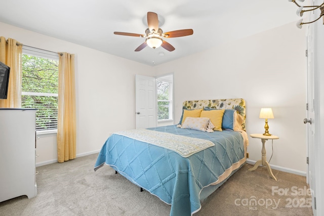bedroom featuring baseboards, multiple windows, and light carpet