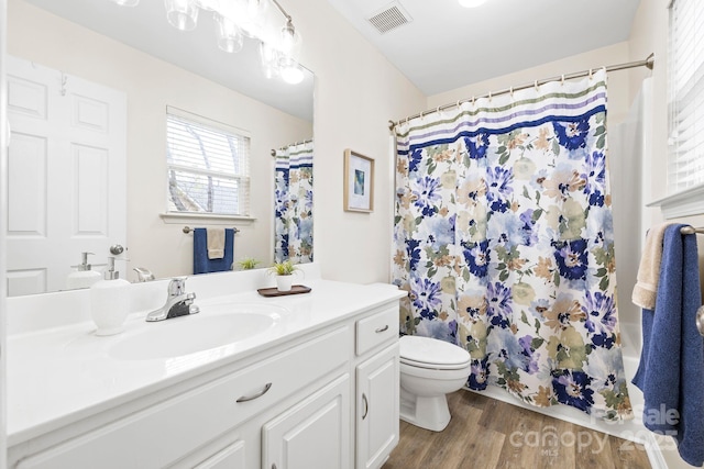 bathroom featuring vanity, a shower with curtain, visible vents, toilet, and wood finished floors