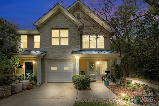 traditional-style house with a standing seam roof, stucco siding, metal roof, an attached garage, and driveway