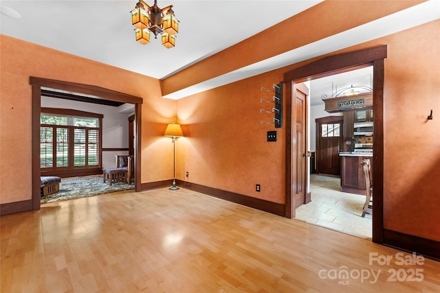 spare room featuring baseboards and light wood-type flooring
