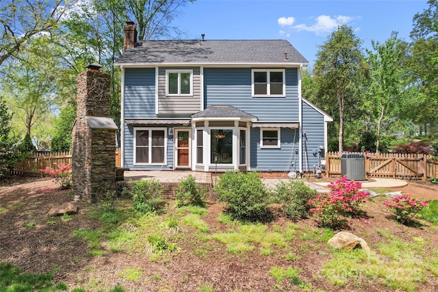 view of front facade featuring central AC unit, a chimney, and fence