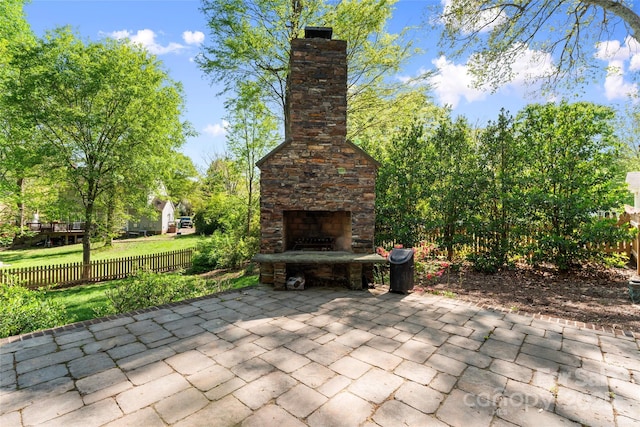 view of patio / terrace featuring fence and an outdoor stone fireplace