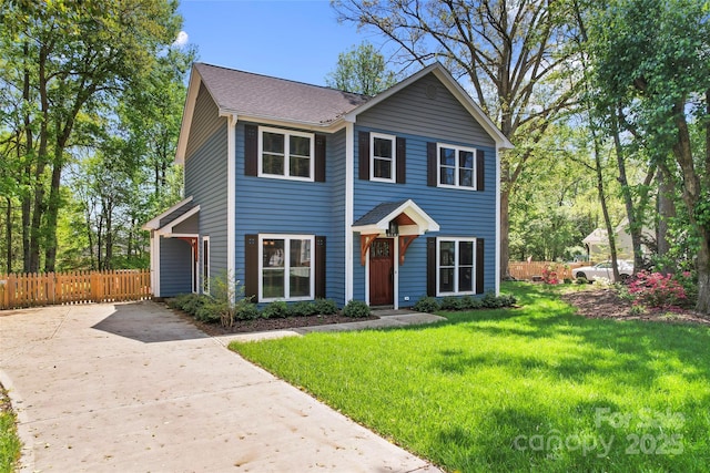 view of front of house featuring a front yard, fence, a shingled roof, and driveway