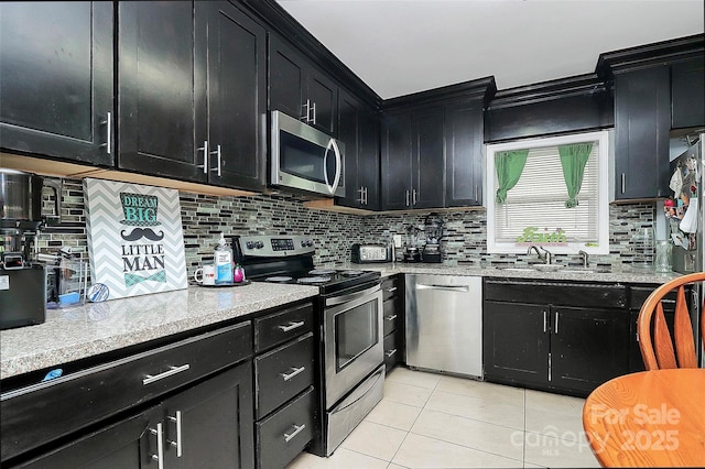 8301 Washington Blvd, Charlotte, NC 28262 - kitchen featuring dark cabinetry, light tile patterned floors, a sink, and stainless steel appliances