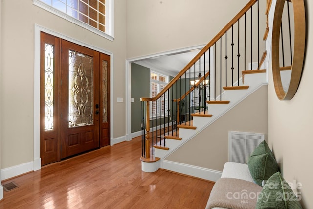 foyer entrance with baseboards, wood finished floors, visible vents, and a wealth of natural light