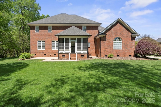 rear view of house with brick siding, a yard, a sunroom, and crawl space